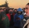 Mujer dialogando con un grupo de manifestantes cubiertos del rostro.