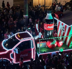 Se observa un camión iluminado de la Coca Cola y muchas personas alrededor.