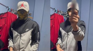 Joven con chamarra nike, gorra y pañoleta sobre el rostro sosteniendo un arma de fuego al lado de un perchero con ropa