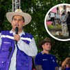 El político Carlos Manzo (con sombrero de paja y chaleco púrpura) habla en un micrófono en un evento al aire libre en un parque. Otros asistentes con sombreros