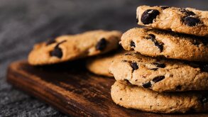 Seis galletas con chispas de chocolate apiladas sobre una mesa de madera.