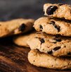 Seis galletas con chispas de chocolate apiladas sobre una mesa de madera.