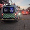 Vista trasera de una ambulancia de la Cruz Verde de Zapopan estacionada al exterior de una casa y detrás de una cinta policial amarilla