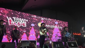 Se observa a varios hombres tocando instrumentos musicales, arriba de un escenario.