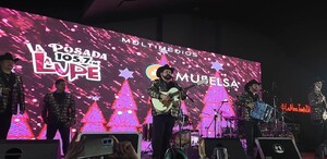 Se observa a varios hombres tocando instrumentos musicales, arriba de un escenario.
