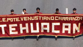 Hombres sosteniendo una manta con el nombre del Centro Escolar Venustiano Carranza.