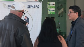 Fotografía tomada a tres personas de espaldas, mientras dialogan al exterior del Semefo de Puebla.