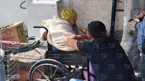 Una mujer anciana en una silla de ruedas platicando con un hombre joven.