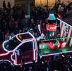 Se observa un camión iluminado de la Coca Cola y muchas personas alrededor.