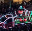 Se observa un camión iluminado de la Coca Cola y muchas personas alrededor.