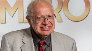 Eduardo Manzano con traje café y sonriendo.