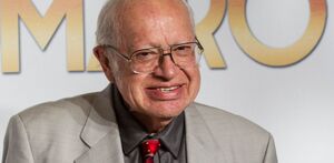 Eduardo Manzano con traje café y sonriendo.