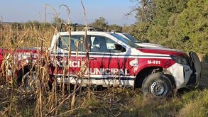 Una patrulla en color rojo con blanco en medio de un terreno baldío.