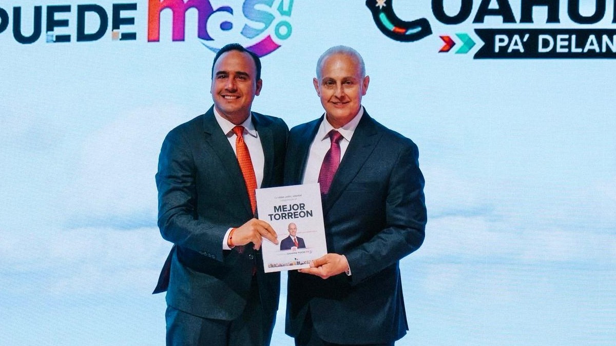 Manolo Jiménez, gobernador de Coahuila, junto a Román Cepeda en el informe de gobierno del alcalde de Torreón. Ambos sostienen el documento oficial del mismo.