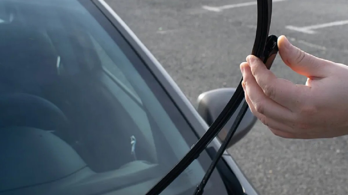 Hombre sosteniendo un vidrio de auto con guantes negros
