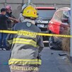 Bombero de Guadalajara de espaladas y detrás de una cinta policiaca ingresando a un taller mecánico donde hay automóviles y otras personas de pie