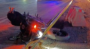 Motocicleta con faro aún encendido tumbada en la Carretera Chapala-Guadalajara durante la noche con una cinta policiaca enfrente y conos de protección al lado