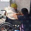 Una mujer anciana en una silla de ruedas platicando con un hombre joven.