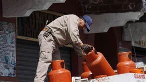 un repartidor de gas lp baja un tanque de su camión en puebla