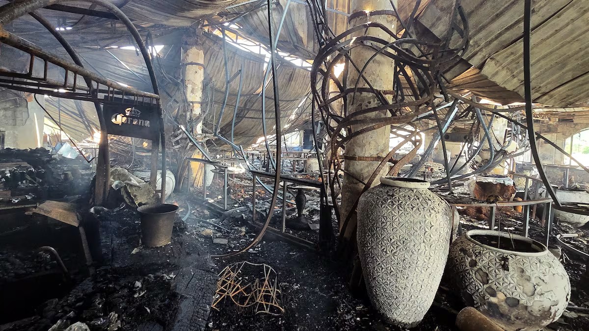 El interior de un restaurante o local comercial totalmente destruido por un incendio. El techo y las vigas metálicas están colapsados y quemados. Se ven grandes