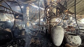 El interior de un restaurante o local comercial totalmente destruido por un incendio. El techo y las vigas metálicas están colapsados y quemados. Se ven grandes