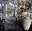 El interior de un restaurante o local comercial totalmente destruido por un incendio. El techo y las vigas metálicas están colapsados y quemados. Se ven grandes