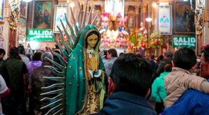 Figura de la Virgen de Guadalupe siendo sostenida por un hombre visto de espaldas, dentro del Santuario de la Virgen de Guadalupe en Guadalajara