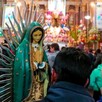 Figura de la Virgen de Guadalupe siendo sostenida por un hombre visto de espaldas, dentro del Santuario de la Virgen de Guadalupe en Guadalajara