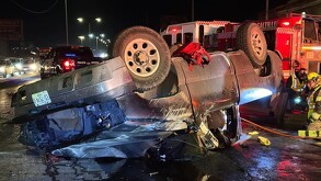 Se observa una camioneta color gris destrozada y al lado unos paramédicos.