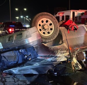 Se observa una camioneta color gris destrozada y al lado unos paramédicos.
