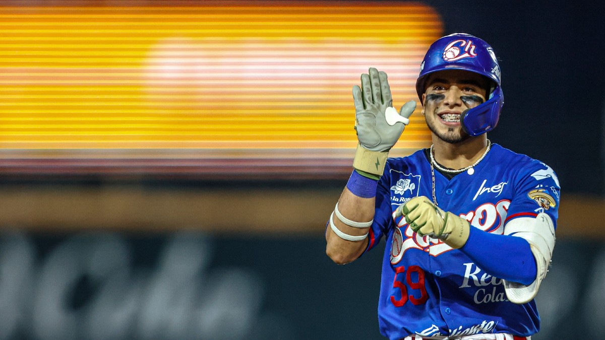 Un jugador de béisbol de los Charros de Jalisco (uniforme azul) sonríe y levanta el guante con la mano abierta, celebrando en el campo durante un partido