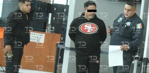 Se observa a tres hombres, entre ellos un policía, y el que está a lado viste sudadera negra con letras SF.