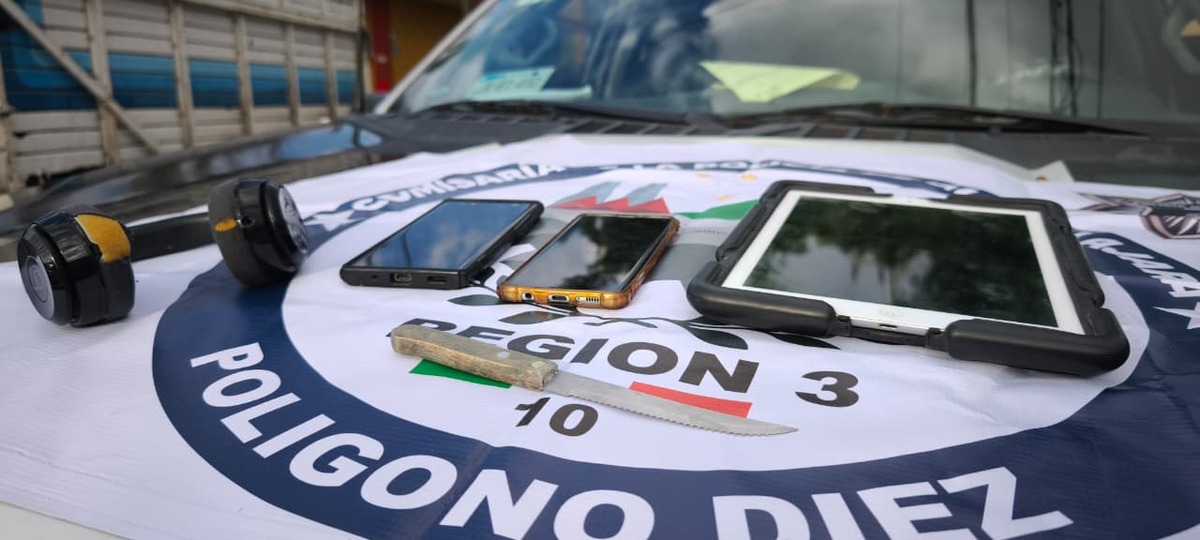 Audífonos, dos teléfonos celulares, una tablet y un cuchillo de cocina sobre una lona de la comisaría de Zapopan sobre el cofre de una patrulla de policía