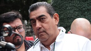 Hombre vestido de blanco mirando hacia la cámara en el zócalo de Puebla.