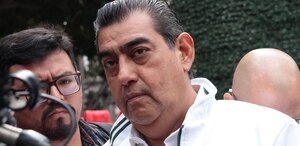 Hombre vestido de blanco mirando hacia la cámara en el zócalo de Puebla.