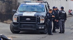 Oficiales parados junto a una patrulla de la Policía Municipal de Guadalajara estacionada en calles donde se hallaron a tres personas