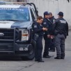 Oficiales parados junto a una patrulla de la Policía Municipal de Guadalajara estacionada en calles donde se hallaron a tres personas