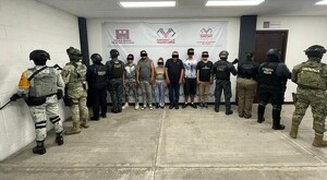 Hombres y mujeres de pie y con los ojos censurados en instalaciones de la Fiscalía de Chiapas con militares parados de espaldas a los costados