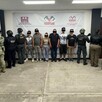 Hombres y mujeres de pie y con los ojos censurados en instalaciones de la Fiscalía de Chiapas con militares parados de espaldas a los costados