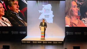 Se observa a un hombre en un escenario hablando frente a personas.