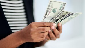 Persona contando sus dólares estadounidenses.