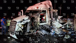 Se observa un tráiler blanco destrozado y unos hombres a un costado.