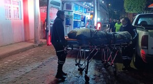 Paramédicos de Tlaquepaque transportando al hombre herido sobre un camilla a punto de ingresarlo dentro de una ambulancia durante la madrugada