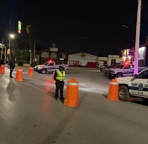 Se observa a unos policías de tránsito en la vialidad y a unos carros en tránsito.