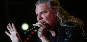 Fernando Olvera, vocalista de Maná, con un micrófono sobre las manos.