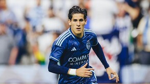 Un joven futbolista del Sporting Kansas City (uniforme azul marino) corre en el campo. El jersey tiene el logo de 