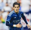 Un joven futbolista del Sporting Kansas City (uniforme azul marino) corre en el campo. El jersey tiene el logo de 