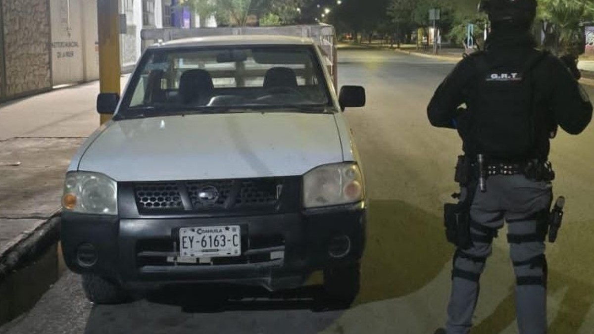 Camioneta en color blanco y al lado un hombre vestido todo en color negro