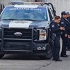 Oficiales parados junto a una patrulla de la Policía Municipal de Guadalajara estacionada en calles donde se hallaron a tres personas