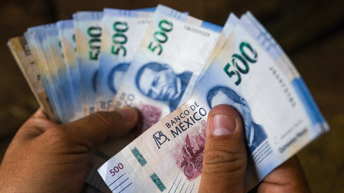 Se observa una mano que tiene varios billetes azules de 500 pesos.